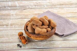 A bowl of peanuts and a napkin on a wooden table photo
