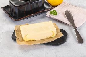 A butter block on a cutting board next to a knife and a lemon photo