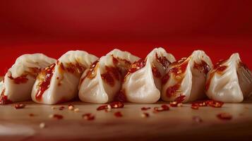 A close-up of dumplings drizzled with spicy sauce on a red background. photo