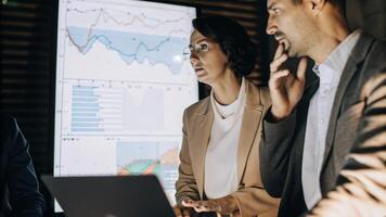 A focused shot showing a team of professionals engaged in discussion with a sleek holographic interface displaying comparative analytics of competitors highlighting key metrics in. photo