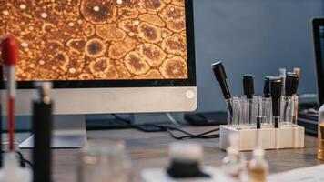 A focused shot of pipettes and beakers on a cluttered table with a highresolution computer screen showing detailed cellular structures and analysis software running.. photo
