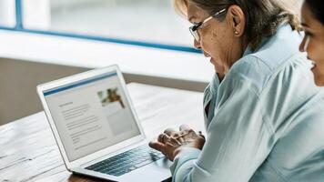 A focused elderly woman leaning closer to her laptop her face illuminated by the screen light as she takes part in a brainstorming session about nutrition hacks that promote. photo
