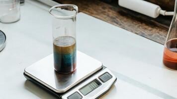 A glass beaker filled with a colorful liquid sits beside a precise digital scale highlighting the meticulous measurement process in a home lab environment.. photo