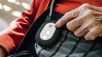Closeup of a health monitoring device clipped to an older adults clothing sensors highlighted in bright light as they engage in light stretching exercises.. photo