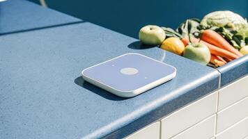 A hightech device resting on a kitchen counter capable of analyzing food intake and nutritional values alongside colorful fruits and vegetables symbolizing the intersection of. photo