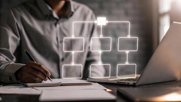 A vibrant holographic graph illustrating resource allocation appears above a desk with a person taking notes and considering workload optimization.. photo