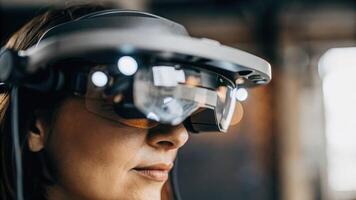 A closeup of a futuristic headset being worn by a participant as they experience a holographic simulation their face illuminated by the immersive virtual environment.. photo