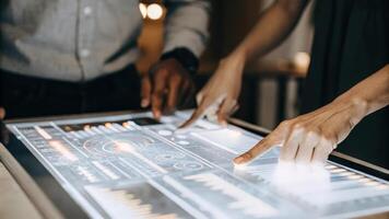 A close view of a sleek holographic workstation illuminated with intricate graphs and animated data as a person navigates through various metrics.. photo