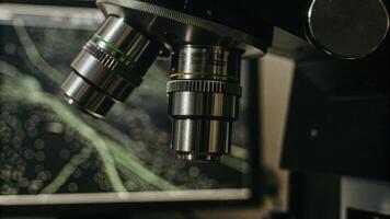 Microscope lenses showing a detailed view of immune cells under observation with digital screens in the background displaying data graphs related to immune response experiments.. photo