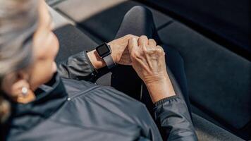 A closeup view of a senior female participant handling a futuristic wearable device her fingers deftly navigating touchsensitive controls while smiling at the digital health. photo