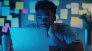 A concentrated face illuminated by the blue light of a laptop showcasing a participant deep in thought surrounded by coffee cups and sticky notes filled with brainstorming ideas an photo
