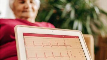 A closeup of a biofeedback monitor displaying heart rate variability with a senior womans attentive face in the background illuminated by warm LED lights signifying her engagement. photo