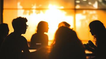 the foreground shows silhouettes of students collaborating in small groups their details fading into a soft background photo
