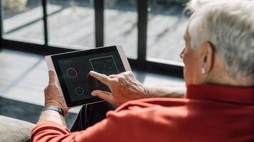 An elderly man uses a finger to rotate a holographic representation of his overall wellness stats the sleek interface surrounding him with an aura of soft light and data.. photo