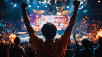 Spectator raising hands cheering at concert in crowded stadium photo