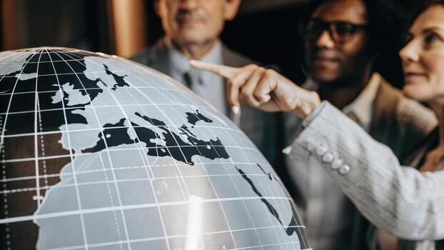 A closeup on a holographic globe displaying market trends and analytics with an exeive pointing at critical data while colleagues observe with keen interest.. photo