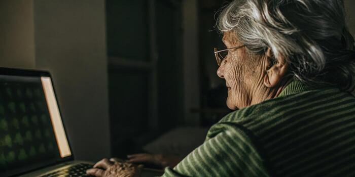 Closeup of an elderly womans face illuminated by the glow of a computer screen with gentle lines of concentration as she participates in an interactive memory game through her. photo