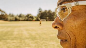 A closeup shot of an older athlete in a sports field with smart glasses displaying hydration levels and weather conditions highlighting the integration of technology and physical. photo