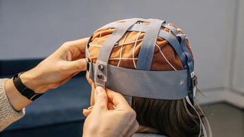 A closeup image of a user adjusting the fit of a DIY EEG cap made from breathable fabric showing the importance of comfort and functionality in wearable brain monitoring. photo