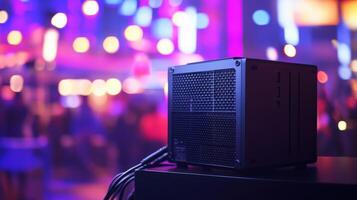 A side angle of the encoder box displaying its cooling vents and ventilation design set against an outoffocus background of a vibrant event in progress emphasizing its compactness an photo