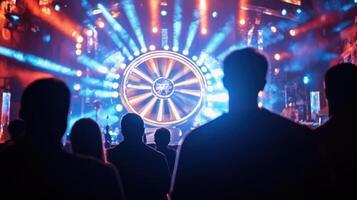 A moment of suspense as a contestant prepares to spin a giant prize wheel surrounded by flashing lights and dramatic sound effects with the host encouraging them while the audienc photo