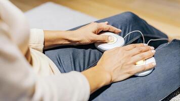 Closeup of a participants hands resting on their knees with the neurostimulation device subtly illuminated embodying tranquility and modern mindfulness practices intertwined.. photo
