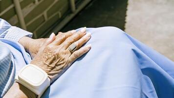 Hands of an older person resting on a lap with delicate designs of the neural stimulation device contrasting against their skin symbolizing the blend of wisdom and innovation.. photo