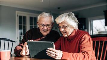 An older couple huddled together at a kitchen table sharing a tablet their expressions a mix of curiosity and excitement as they explore digital health apps that help optimize. photo