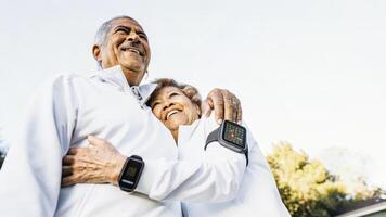 A senior couple embraces their fitness trackers linked as they share a moment of joy after completing a shared exercise session both revealing glowing metrics on their displays.. photo