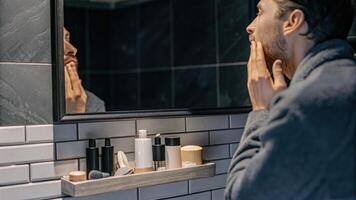 A thoughtful male figure gazing into a mirror showcasing transformative skincare routines with an array of environmentallyfriendly products neatly arranged around him.. photo