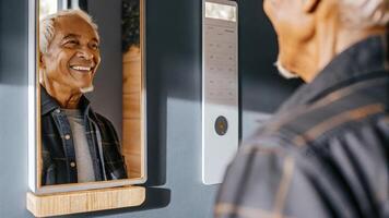 An elderly man smiling as he interacts with a smart mirror which shows personalized reminders for medication and hydration capturing his sense of accomplishment in managing his. photo
