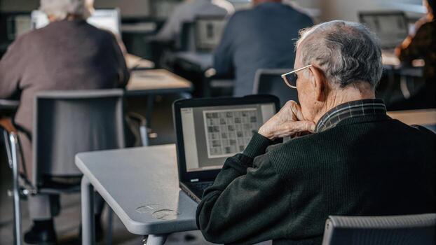 A thoughtful elderly man gazes at the screen a word puzzle open in front of him showcasing the diversity of activities involved in the cognitive enhancement workshop.. photo