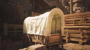 Covered wagon resting near wooden structures in a rustic western setting video