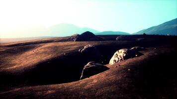 Vast rocky landscape at dawn with lush hills and mountains in background video