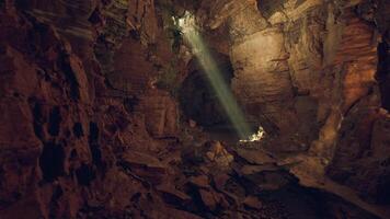 Light streaming through a cave opening in a rocky underground landscape video