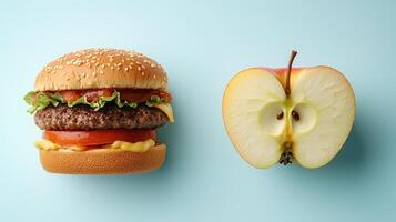 Juxtaposition of hamburger and half apple on blue background photo