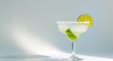 Refreshing classic margarita served in a stylish coupe glass with sea salt and lime on a bright background. photo