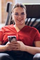 A businesswoman resting on a short break from work in a modern startup coworking center, using her smartphone to unwind and recharge. photo