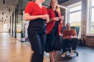 A diverse group of business professionals collaborates in a modern startup coworking center, utilizing a mix of paper-based and technological tools such as mobile phones and computers to collectively photo