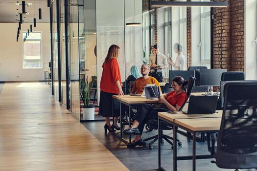 A diverse group of business professionals collaborates in a modern startup coworking center, utilizing a mix of paper-based and technological tools such as mobile phones and computers to collectively photo