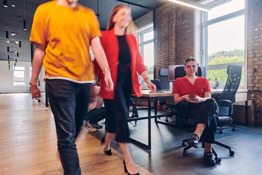 A diverse group of business professionals collaborates in a modern startup coworking center, utilizing a mix of paper-based and technological tools such as mobile phones and computers to collectively photo