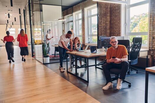 A diverse group of business professionals collaborates in a modern startup coworking center, utilizing a mix of paper-based and technological tools such as mobile phones and computers to collectively photo