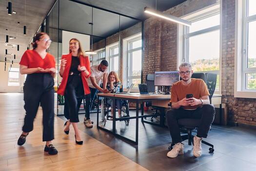 A diverse group of business professionals collaborates in a modern startup coworking center, utilizing a mix of paper-based and technological tools such as mobile phones and computers to collectively photo