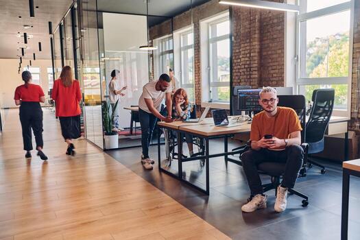 A diverse group of business professionals collaborates in a modern startup coworking center, utilizing a mix of paper-based and technological tools such as mobile phones and computers to collectively photo