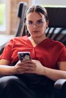 A businesswoman resting on a short break from work in a modern startup coworking center, using her smartphone to unwind and recharge. photo