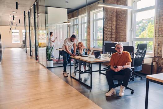 A diverse group of business professionals collaborates in a modern startup coworking center, utilizing a mix of paper-based and technological tools such as mobile phones and computers to collectively photo