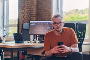 A modern businessman takes a relaxing break from work, using his smartphone to unwind and recharge during his pause photo