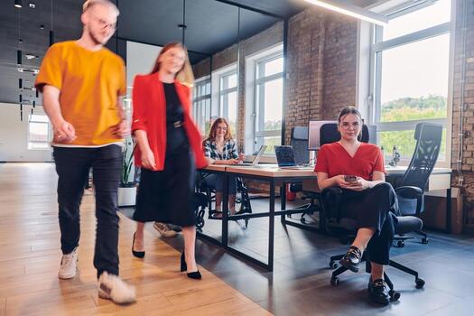 A diverse group of business professionals collaborates in a modern startup coworking center, utilizing a mix of paper-based and technological tools such as mobile phones and computers to collectively photo