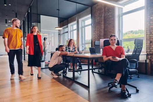 A diverse group of business professionals collaborates in a modern startup coworking center, utilizing a mix of paper-based and technological tools such as mobile phones and computers to collectively photo