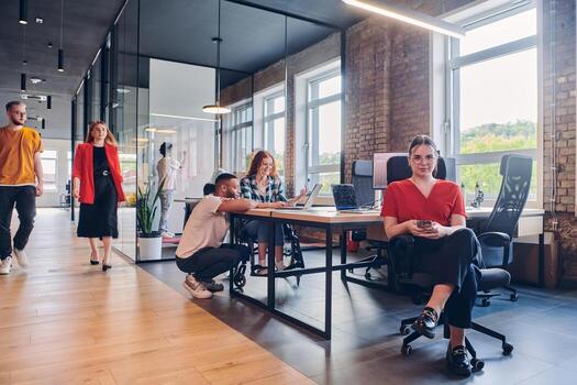 A diverse group of business professionals collaborates in a modern startup coworking center, utilizing a mix of paper-based and technological tools such as mobile phones and computers to collectively photo